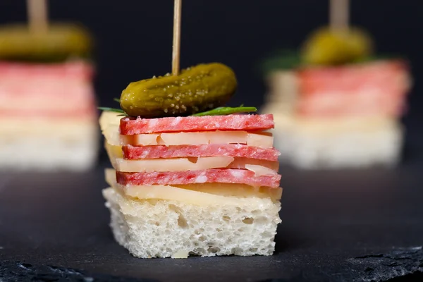 Pequeños bocadillos de canapé con salami, queso y pepinillo en escabeche — Foto de Stock