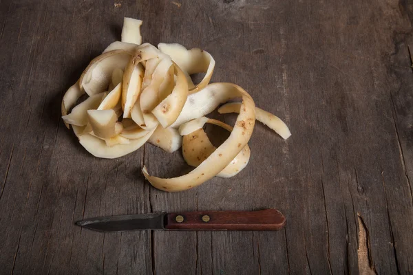 Potatoes peelings on old wooden background — Stock Photo, Image