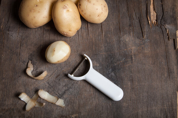 Картофель с кожурой на старом деревянном фоне
