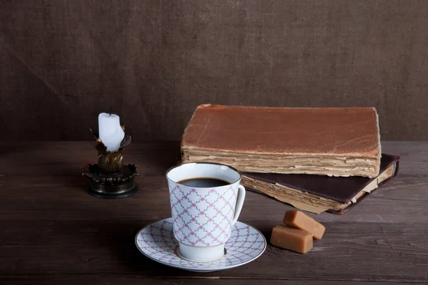 Cărți vechi, ceașcă de cafea, bomboane și lumânări antice pe masă . — Fotografie, imagine de stoc