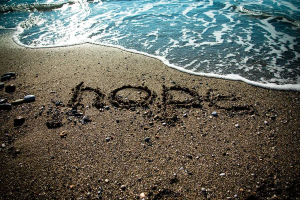 Fala i napis "Nadzieja" na wybrzeżu żwirowa. Selectiv — Zdjęcie stockowe