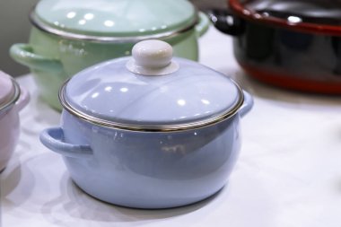 Birçok emaye kaplı çelik metal, çok renkli, modern tencere, emaye tezgahları mutfakta bir rafta duruyor. Ev eşyaları, bulaşıklar, mutfak aletleri. Dükkan penceresi, yerli ürünlerin satışı, iç ayrıntılar