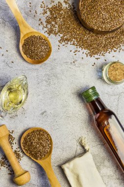 Şişedeki keten tohumu yağı, keten tohumu, salata sosu et suyunda salata sosu omega-3 antioksidan vitaminleri ve yağ asitleri bir masada doğal açık gri beton arka planda düz bir görünüm sergiliyor.