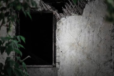 Arka plan korku konsepti, ormandaki ağaçların arasında yanan ev. Yangından sonra yıkılan grunge binalarından oluşan korkunç eski püskü dokuma duvarlar ve gizemli gölgelerin oluşturduğu çerçevelenmemiş pencereler korkuya neden oluyor.