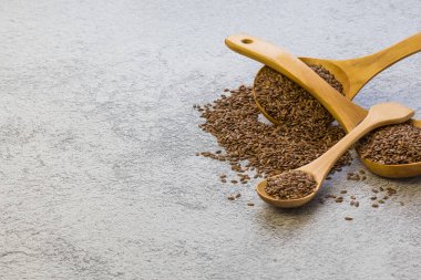 Beton zeminde üç tahta kaşıkta keten tohumu, kolesterolü azaltan bir diyet ürünü, bir omega-3 kaynağı, B ve C vitamini, iyot, fosfor, potasyum, magnezyum, nikel