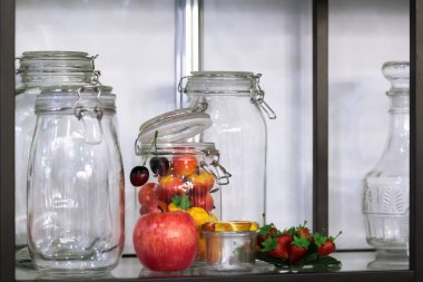 Rafta konserve sebzeler, meyveler ve meyveler için şarjörü olan çeşitli yeni boş kavanozlar var..