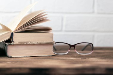 Çevrimdışı eğitim kavramı okuma öğrenme bilgeliği, görme bozukluğu, açık kitap ve gözlükler tahta bir masanın üzerinde fotokopi alanı olan beyaz tuğla duvar arka planına karşı.