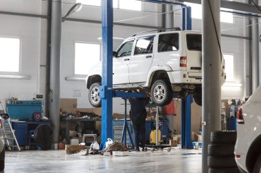 Saratov, Rusya - 04.10.2021: Araç servis istasyonu, atölyedeki asansörde özel ekipmanla beyaz bir UAZ Patriot 'un onarımı