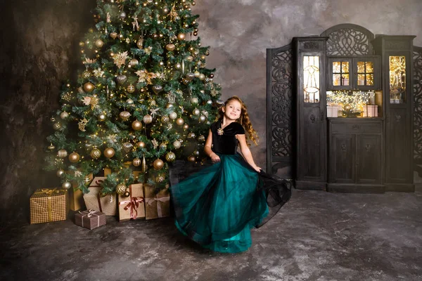 Little girl smiling and dancing near the Christmas tree.