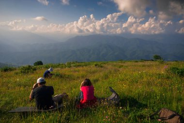 Gürcistan, Racha - 7 Temmuz 2013: Bir grup gezgin dağların muhteşem manzarasının tadını çıkarıyor.