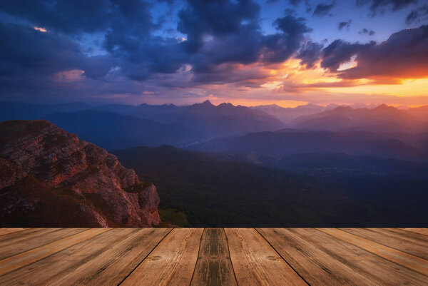 Summer beautiful background with sunrise over mountains and empty wooden table in nature outdoor. Natural template landscape.