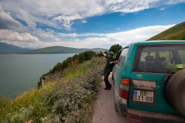 Gürcistan, Javakheti - 25 Temmuz 2015: Gezgin adam muhteşem bir Göl manzarasının keyfini çıkarıyor.