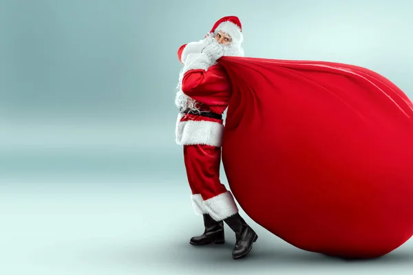 Portrait of a cheerful Santa Claus in a red suit carries a big bag, light background. Concept for christmas eve, vacation, holiday banner, new year. 3D illustration, 3D render