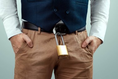 Close-up of a gold padlock hanging from a man's belt. The concept of marital fidelity, celibacy, treason, chastity belt clipart