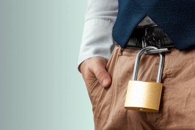 Close-up of a gold padlock hanging from a man's belt. The concept of marital fidelity, celibacy, treason, chastity belt clipart
