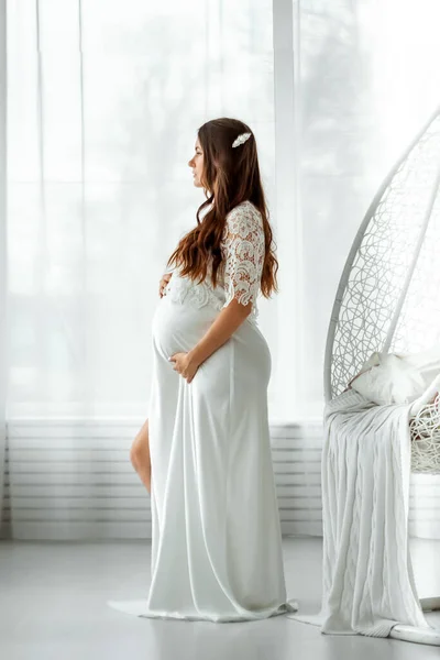 Μια Έγκυος Άσπρα Ρούχα Στέκεται Ένα Ελαφρύ Φόντο Όμορφη Κοιλιά — Φωτογραφία Αρχείου