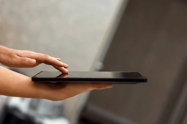 A female hand presses on the screen of a digital tablet close-up, side view. New technology concept, multimedia