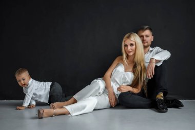 Güzel bir Avrupalı evli çiftin fotoğrafı, genç bir kız ve küçük bir oğlu olan bir adam, kamera önünde birlikte poz veriyorlar. Siyah özgeçmiş, modern aile kavramı, aile ilişkileri.