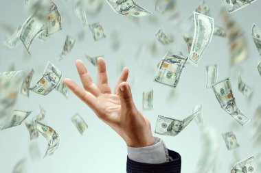 İş adamının eli arka planda düşen dolarları yakalıyor. Yatırım, temettü, faiz, banka mevduatları kavramı