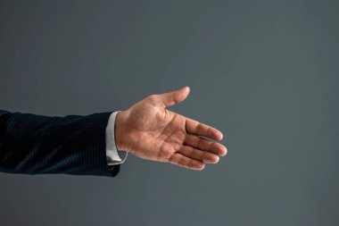 Takım elbiseli erkek, gri arka planda olumlu bir hareket gösteriyor. Konsept tamam, onay, yakın çekim