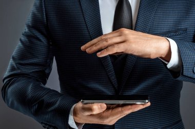 Takım elbiseli bir işadamı akıllı telefonu elinde tutuyor. Çevrimiçi iş konsepti, ağ oluşturma, serbest çalışma