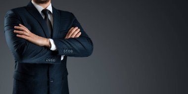 Takım elbiseli bir adam gri bir arka planda kollarını kavuşturmuş duruyor. Kavramsal iş adamı, iş iletişimi. Yakın plan.