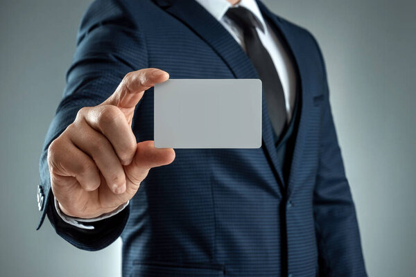 A man in a suit hands close-up shows a business card. mockup, layout. Concept for networking, business dating, important connections. Shot on a gray background