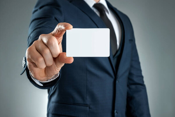 A man in a suit hands close-up shows a business card. mockup, layout. Concept for networking, business dating, important connections. Shot on a gray background