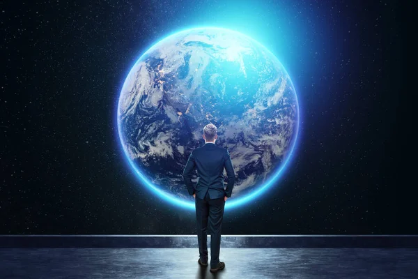 A man in a business suit, a businessman stands against the background of the globe. Mixed media. Concept Global networks and international business. Elements of this image furnished by NASA