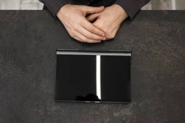 Masasında boş ekranı olan siyah bir tabletin yanında bir iş adamının elleri. Kavramsal işadamı, ofis, finans