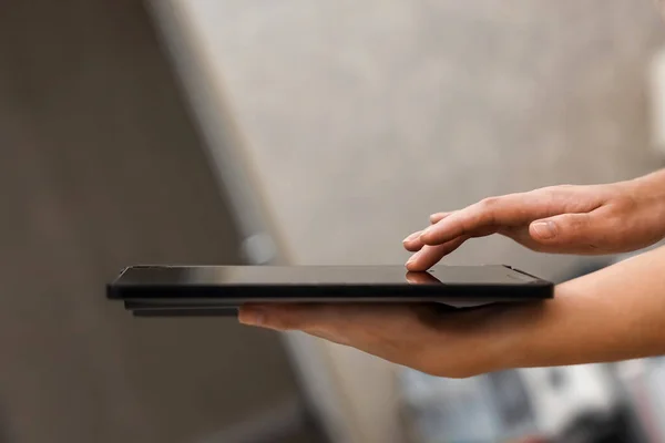 A female hand presses on the screen of a digital tablet close-up, side view. New technology concept, multimedia