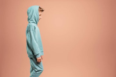 Turkuaz takım elbiseli bir çocuk bej arka planda poz veriyor ve kameraya bakıyor. Çocuk stüdyo resmi. Çocukluk yaşam tarzı konsepti