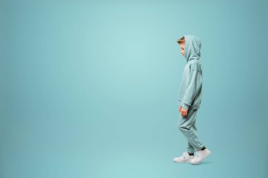 Turkuaz kıyafetli küçük bir kız poz veriyor ve turkuaz arka planda aylaklık ediyor, kameraya bakıyor. Çocuk stüdyo resmi. Çocukluk yaşam tarzı konsepti