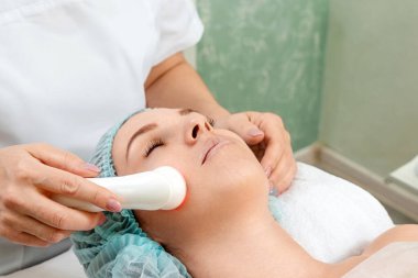 Yüz derisinin ışıkla tedavi edilmesi için tıbbi, kozmetik prosedürü, yüzündeki gözenekleri temizlemek için fototerapi. Cilt bakımı, kozmetik prosedürleri.