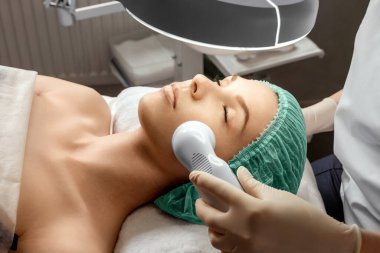 Güzellik uzmanı kızın derisini özel bir aletle temizliyor. Yüz hijyeni, kozmetik prosedürleri, cilt bakımı, cilt temizleme, spa, donanım kozmetolojisi.