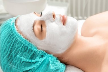 Kızın yüzü kozmetik bir maskeyle kaplıydı, yakın plan. Cilt bakımı, güzellik uzmanı, kaplıca tedavisi, yüz hijyeni.