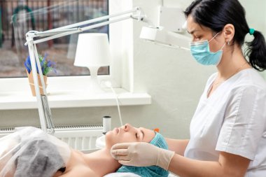 Kızın yüzü spa ameliyatından sonra temizlenecek, yakın plan. Cilt bakımı, güzellik uzmanı, kaplıca tedavisi, yüz hijyeni.