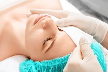 Kızın yüzü spa ameliyatından sonra temizlenecek, yakın plan. Cilt bakımı, güzellik uzmanı, kaplıca tedavisi, yüz hijyeni.