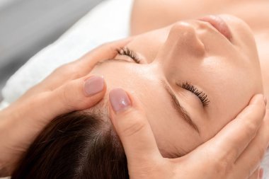 Güzel bir kızın yüzüne masaj yapılıyor, yakın plan çekimde. Cilt bakımı, güzellik uzmanı, kaplıca tedavisi, yüz hijyeni.