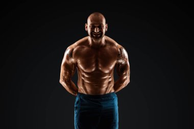 Siyah arka planda poz veren dövmeli erkek vücut geliştirici. Spor konsepti, kas grupları, vücudunuza dikkat edin.