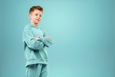 Mavi arka planda mavi takım elbiseli yakışıklı bir çocuk. Bir çocuğun stüdyo portresi, modern tasarım, modaya uygun arka plan, turkuaz. Boşluğu kopyala