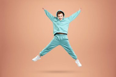 Portre, bej arka planda mavi takım elbiseli yakışıklı bir çocuk. Bir çocuğun stüdyo portresi, modern tasarım, modaya uygun arka plan, turkuaz. Boşluğu kopyala