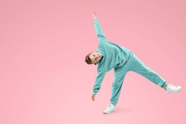 Portre, pembe arka planda mavi takım elbiseli yakışıklı bir çocuk. Bir çocuğun stüdyo portresi, modern tasarım, modaya uygun arka plan, turkuaz. Boşluğu kopyala