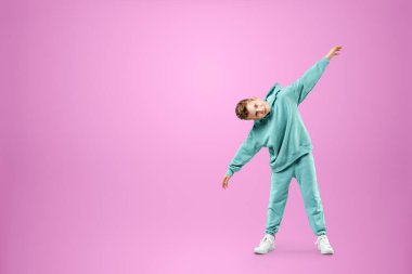 Portre, pembe arka planda mavi takım elbiseli yakışıklı bir çocuk. Bir çocuğun stüdyo portresi, modern tasarım, modaya uygun arka plan, turkuaz. Boşluğu kopyala