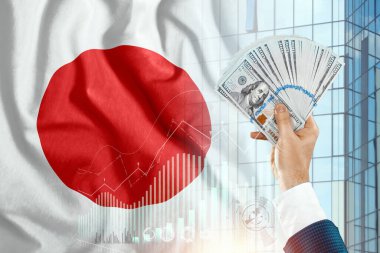 Japon bayrağının arka planına karşı bir adamın elindeki para. Japon geliri. Japonya sakinlerinin mali durumu, vergiler, krediler, ipotekler. Japonya 'nın hükümet borcu