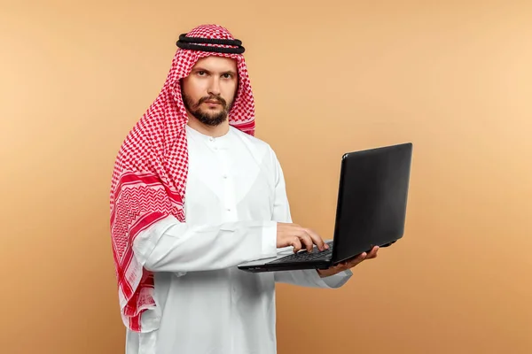 An Arab man, a businessman, a sheikh works at a laptop. Investments, business, work via the Internet, online contracts