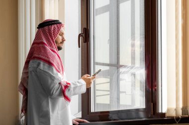 Bir Arap, bir işadamı, bir şeyh bir gökdelenin önünde duruyor. Yatırımlar, iş, internet üzerinden çalışma, çevrimiçi sözleşmeler