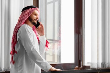 Bir Arap, bir işadamı, bir şeyh bir gökdelenin önünde duruyor. Yatırımlar, iş, internet üzerinden çalışma, çevrimiçi sözleşmeler