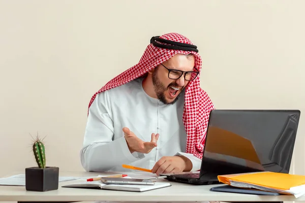 An Arab man, a businessman, a sheikh works at a laptop. Investments, business, work via the Internet, online contracts