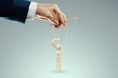 Erkek eli, kuklacı kuklayı kontrol eder, oyuncak bebek selamı, asker. Ordu konsepti, emirler, manipülasyon, kontrol ordusu.